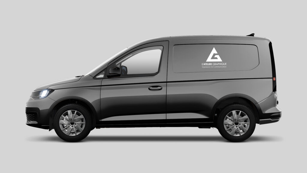 Marquage publicitaire blanc avec le logo de L'Atelier Graphique sur le panneau latéral d'un véhicule utilitaire gris