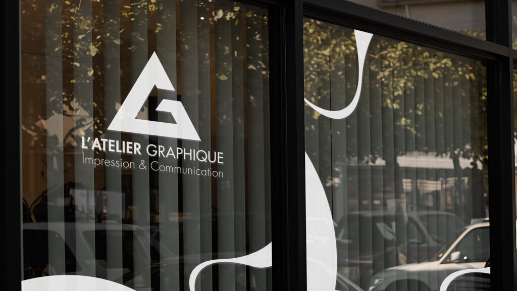 Vitrophanie en vinyle blanc avec logo et motifs graphiques collés sur la vitrine extérieure des locaux de L'Atelier Graphique